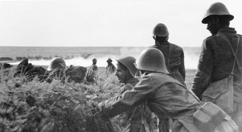 Archival photograph of Romanian infantrymen in helmets beside earthworks on the steppe.